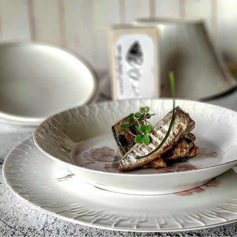 petits maquereaux fumés à l'huile d'olive sur une assiette blanche avec motifs floraux