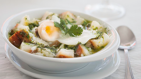 Açorda à la portugaise dans une assiette blanche avec oeuf poché et coriandre